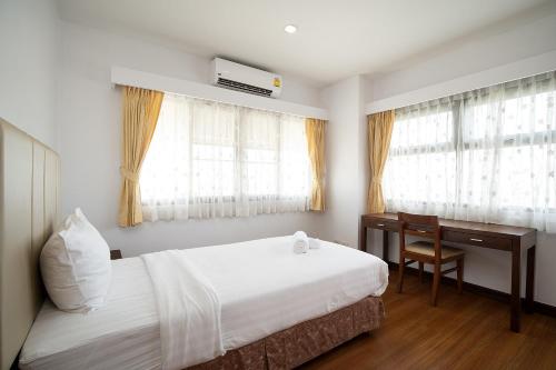 a bedroom with a bed and a desk and windows at Lasalle Suites Hotel & Residence in Bangkok