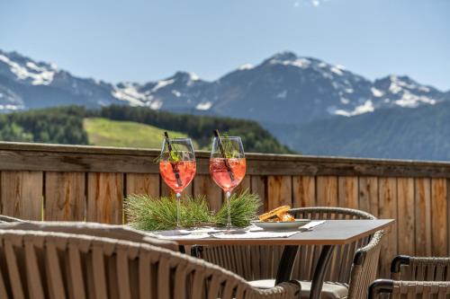 two glasses of wine sitting on a table on a balcony at Naturhotel Falknerhof in Niederthai