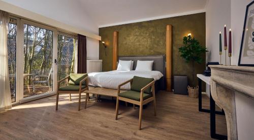 a bedroom with a bed and two chairs and a window at Hotel Duinrand Drunen in Drunen