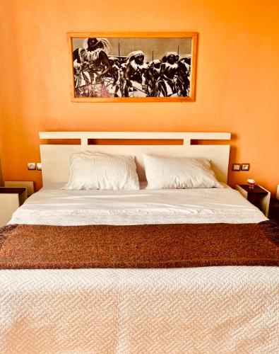 a bedroom with a white bed with a picture on the wall at Mona Rusizi in Cyangugu