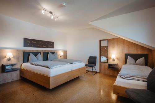 a bedroom with two beds and a chair in it at Hotel am Haidel in Hinterschmiding