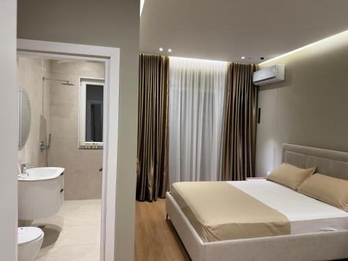 a bedroom with a bed and a bathroom with a sink at Gysi`s Hotel & Restaurant - Near Tirana in Tapizë