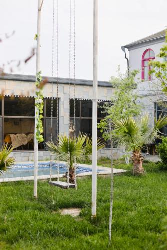 a yard with palm trees in front of a building at Villa Verde w Warm Pool, BBQ, Concierge in Baku