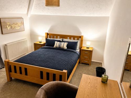 a bedroom with a wooden bed with blue sheets at Cartref in Caerphilly