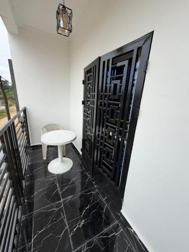 Ein weißer Tisch und ein Hocker auf einem Balkon in der Unterkunft Palace M&E in Douala