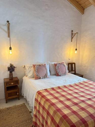 a bedroom with a bed with a checkered blanket at Papoila in Grândola