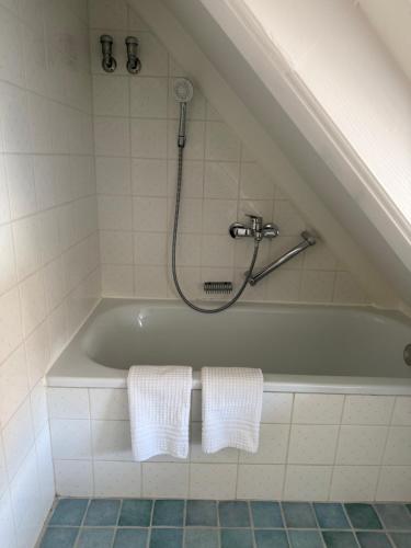 a bathroom with a bath tub with a shower and towels at Friesenhof Süderende Apt.4 in Westerland