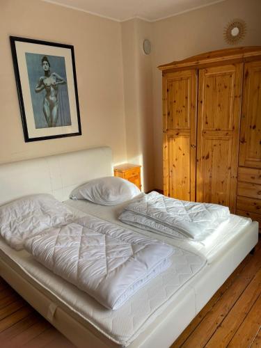 a white bed in a bedroom with a wooden cabinet at Eva Domizil in Laudesfeld