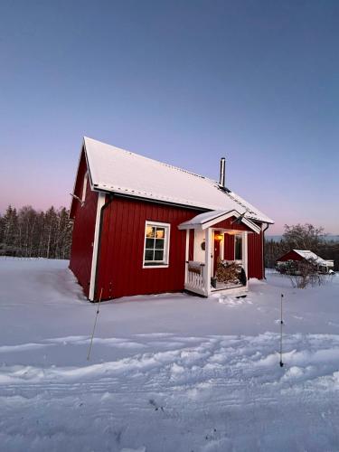 a red barn in the snow with snow covered ground at Farm Stay Between Forests and Meadows in Ulricehamn