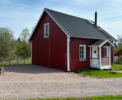 a red barn with a white door on a gravel driveway at Farm Stay Between Forests and Meadows in Ulricehamn