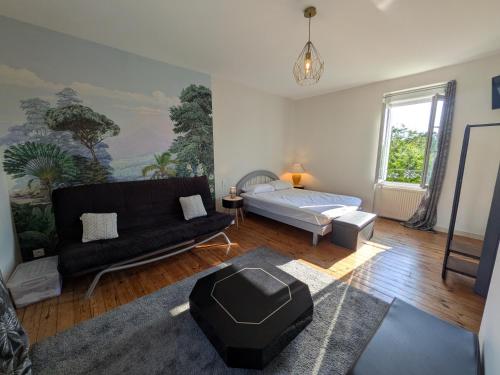 a living room with a black couch and a bed at Gîte de la Vallée du Don in Guéméné-Penfao