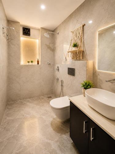 a bathroom with a white sink and a toilet at Coconut Sky 2Bhk Penthouse Baga in Baga