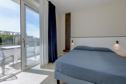 a bedroom with a blue bed and a balcony at Petit Hotel in Caorle