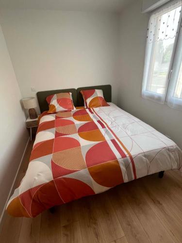 a bed with a colorful comforter in a bedroom at Le Nid Charentais in Cognac