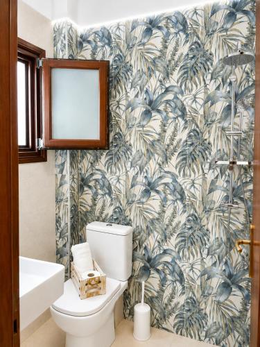 a bathroom with a toilet and a tropical wallpaper at Pension Anastasia in Ammouliani