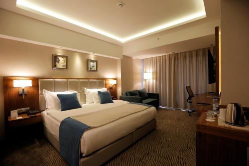 a hotel room with a large bed and a chair at Best Western Premier Karsiyaka Convention & Spa Hotel in Izmir