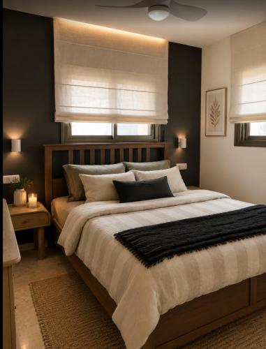 a bedroom with a large bed and two windows at Atelier Luma in Zikhron Ya'akov