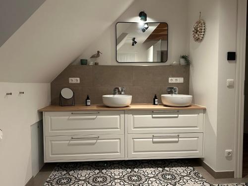 a bathroom with two sinks and a mirror at Linnebarg Hus 4 in Fehmarn