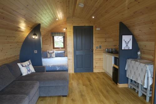 a room with a bed and a couch in a cabin at Ben Loyal Hotel in Tongue