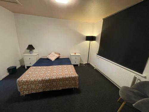 a bedroom with a bed and a large black screen at Cozy & Private House in Roslev