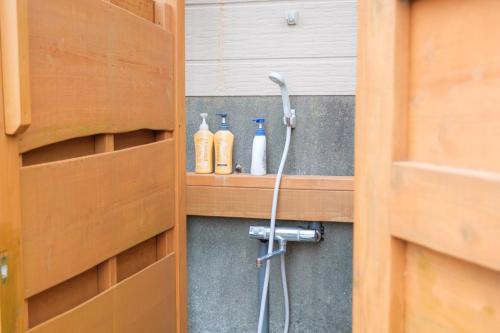a bathroom with a shower head and bottles on a shelf at UMICHIKA AOSHIMA - Private house 一棟貸し in Miyazaki