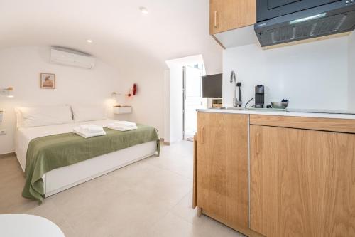 a bedroom with a bed and a kitchen with a sink at Casa Flora Tiny House in Fuzeta