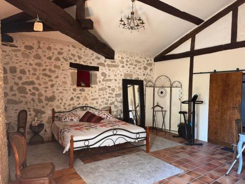 a bedroom with a bed in a room with stone walls at Le Clos Cecile'Ann in Fréchou