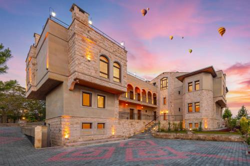 a building with hot air balloons in the sky at Cappadocia Golden Elite in Uçhisar