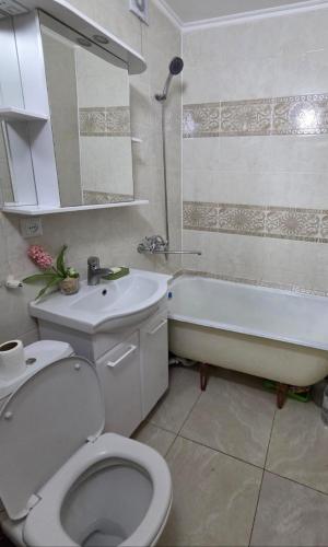 a bathroom with a toilet and a tub and a sink at Сдается квартира у Озера in Balqash