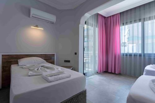 a bedroom with two beds and a window with pink curtains at Best Alanya Hotel in Alanya