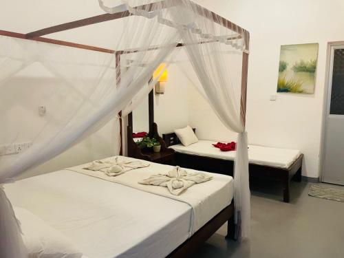 a bedroom with two beds and a canopy bed at Kingly Aroma in Arugam Bay
