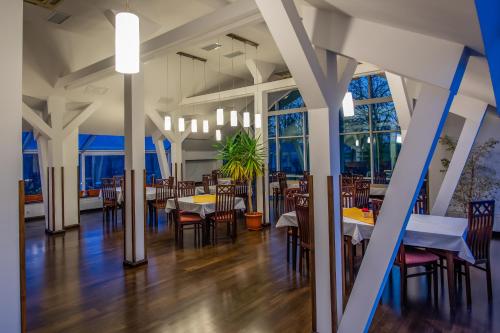 a dining room with tables and chairs and windows at Hotel Maria in Rădăuţi