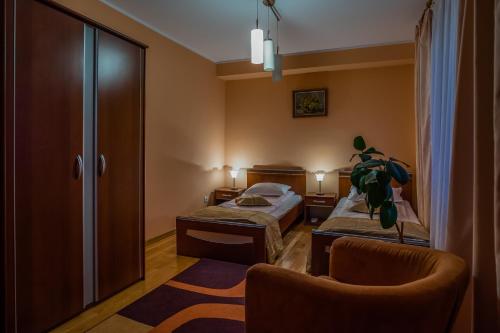 a hotel room with two beds and a chair at Hotel Maria in Rădăuţi