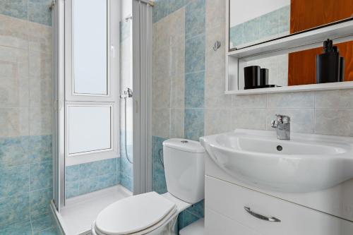 a bathroom with a white toilet and a sink at Celestial Luxury Residences in Ixia