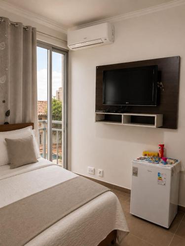 a bedroom with a bed and a flat screen tv at Pousada Yeshua in Paracatu
