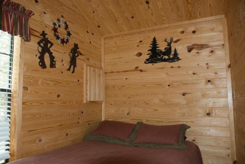 a bedroom with a wooden wall with a bed in it at Medina Lake Camping Resort Cabin 3 in Lakehills