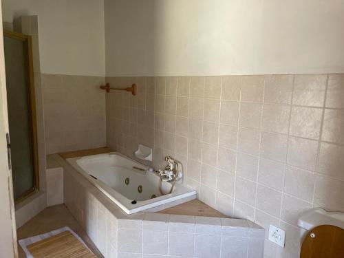 a bath tub in a bathroom with a sink at Shamwari Guesthouse in Kalkheuvel