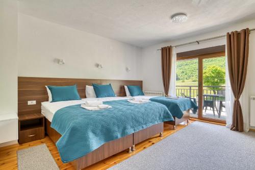 a bedroom with two beds with blue sheets and a window at Milver Apartments Kolasin in Kolašin