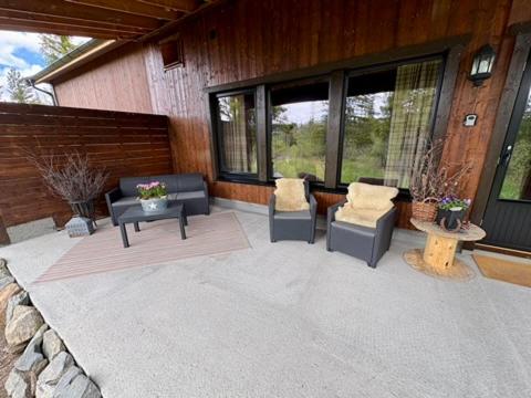 a patio with two chairs and a table and windows at Mountain Stable Apartment Beito in Beitostøl