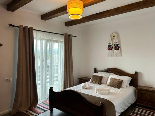 a bedroom with a bed and a large window at Carpathian Soul Maramures in Bogdan Vodă
