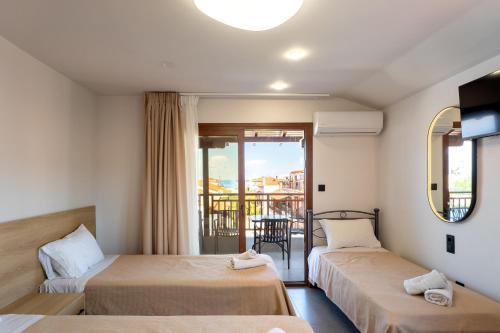 a hotel room with two beds and a balcony at Villa N&D in Ierissos