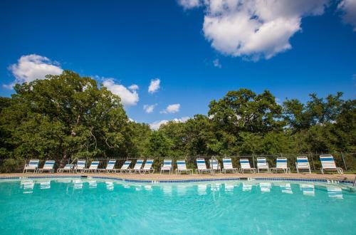 a large swimming pool with chairs and a blue sky at Lake Texoma Camping Resort Cabin 1 in Willow Spring