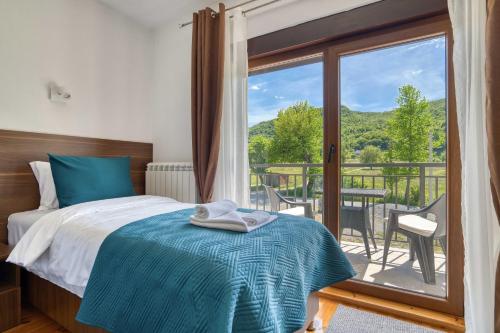 a bedroom with a bed and a balcony with a view at Milver Apartments Kolasin in Kolašin