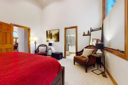 a bedroom with a red bed and two chairs at Elk Trail Retreat in Winter Park