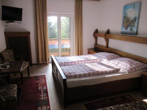 a bedroom with a bed and a table and a window at Waldpension Reisinger in Fladnitz an der Teichalm