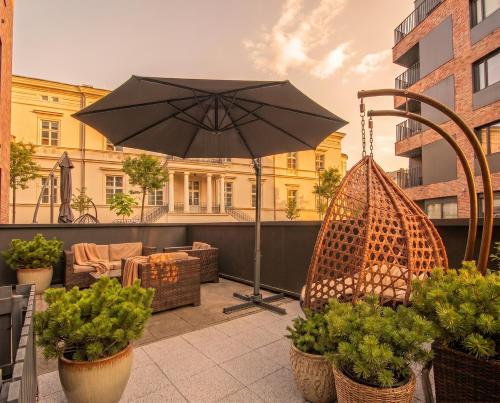 a patio with an umbrella and chairs and plants at City Lights Apartments in Krakow