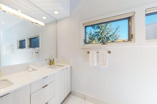 a white bathroom with two sinks and a window at Unveil Vail in Vail
