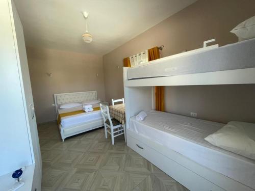 a bedroom with two bunk beds and a chair at Vila Zini in Vlorë