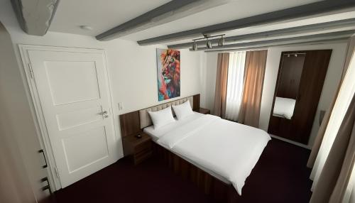 a bedroom with a white bed and a door at Hotel am Kocher in Schwäbisch Hall