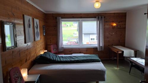 a bedroom with two beds and a window and a desk at Grodås Lake View Apartment in Hornindal
